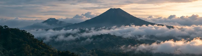 A forested volcano rising above a layer of cloud in Costa Rica at dusk